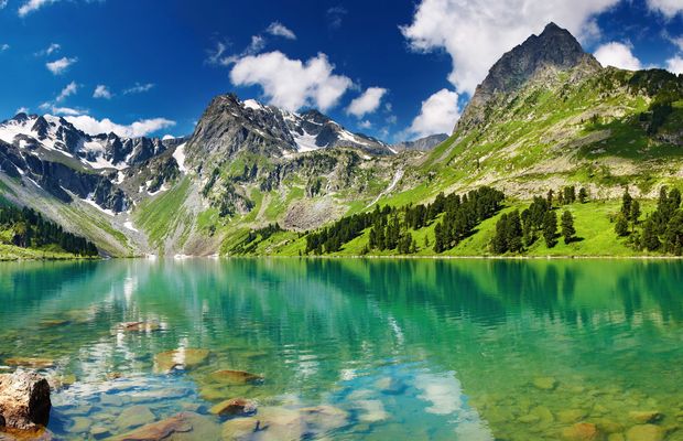 A green alpine lake below snow-streaked peaks