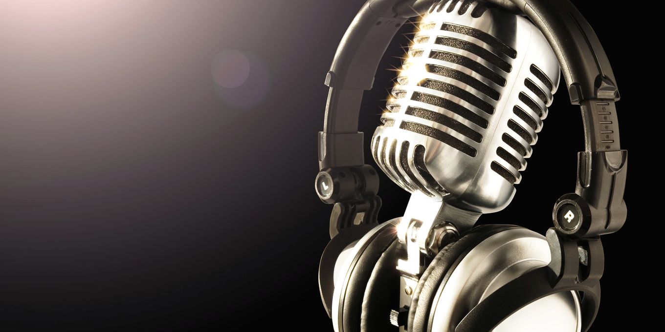 A chrome studio microphone with headphones hung over it