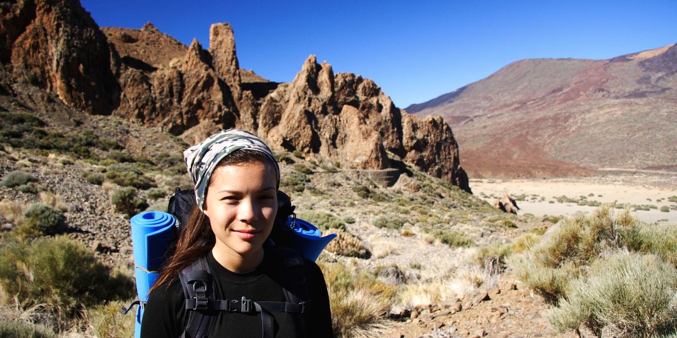 A hiker with a loaded pack and chest strap among volcanic rock